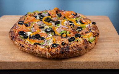 A delicious freshly baked greek pizza with feta cheese, olives, tomato, and green pepper.