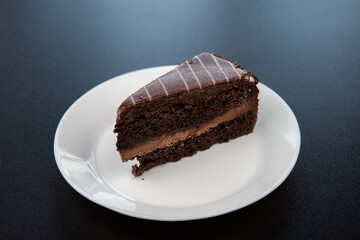 Chocolate cake on white plate on black background