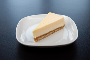 Plain cheesecakes on white plate on black background