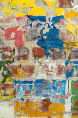Multi-layered abstract background of various colors of painting and graffiti on a brick wall.