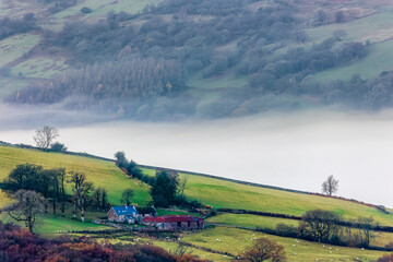 Fototapeta premium Low lying fog and cloud in a rural valley surrounded by farmland and fields (Brecon Beacons, Wales)