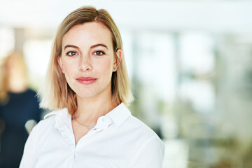 Here to do some serious business. Portrait of an ambitious young woman standing in a modern office with her colleagues in the background. - obrazy, fototapety, plakaty