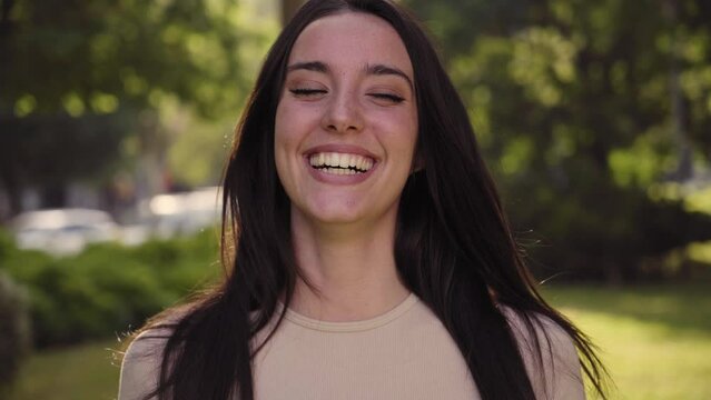 Close up of young smiling woman looking camera. Attractive female laughing standing on street city lifestyle. Beautiful happy girl outdoors. Funny lady emotional expression on urban background. 