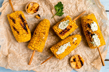 grilled corn on a blue wooden table with green sauce