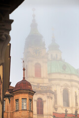 Fototapeta na wymiar Cityscape on a foggy morning - view of the Church of Saint Nicholas in the Mala Strana historical neighbourhood of Prague, Czech Republic
