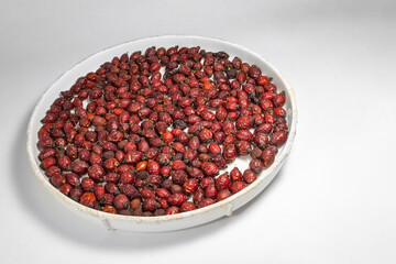 dried rose hips on a plate on white background