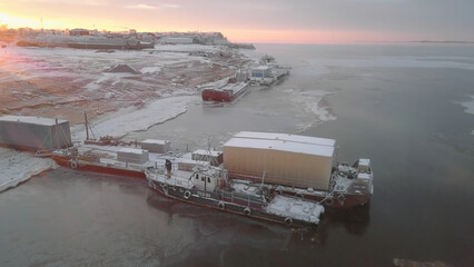 Unloading of sea vessel on coast in winter. Clip. Top view of cargo containers unloading on shore with sea vessel. Sea cargo on coast in winter
