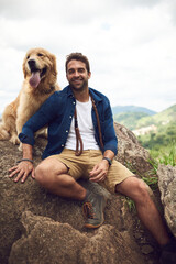 We just love hiking through the mountain. Cropped portrait of a handsome young man and his dog taking a break during a hike in the mountains.