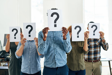Who How What Where When Why. Shot of a group of businesspeople holding questions marks in front of...