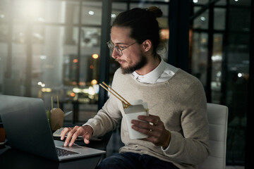 Just a little food and then its back to the task at hand. Cropped shot of a young designer working late in an office.