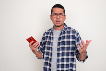 Adult Asian man showing confused expression when holding his mobile phone