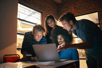 Implement technological solutions to make your business more efficient. Shot of a group of designers working together on a laptop.