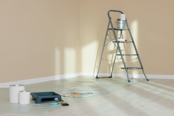Stepladder and painting tools near wall in empty room, space for text