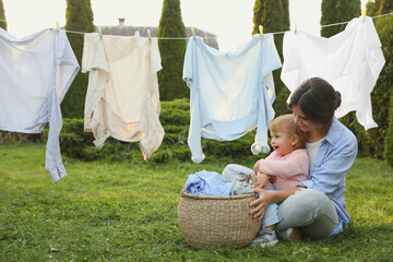 Mother and daughter near washing line with drying clothes in backyard