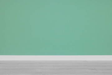 Beautiful light green wall and wooden floor in clean empty room