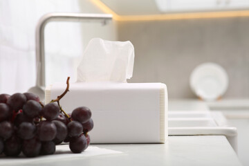 Package of paper towels and ripe grapes near sink in kitchen
