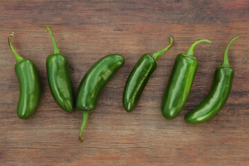 Fresh green jalapeno peppers on wooden table, flat lay