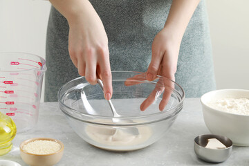 Woman making dough for traditional grissini at light grey marble table indoors, closeup