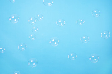 Many beautiful soap bubbles on light blue background