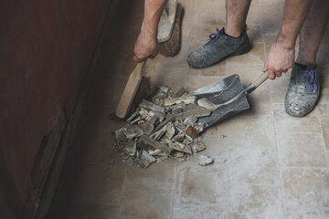 Caucasian male builder sweeps construction debris.