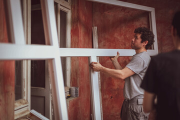 Caucasian male builder carries window frames.