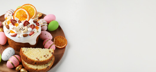 Traditional Easter cake with dried fruits and painted eggs on white table, space for text. Banner design