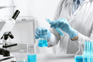 Fototapeta premium Scientist working with beaker and test tube in laboratory, closeup