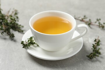 Aromatic herbal tea with thyme on light grey table, closeup