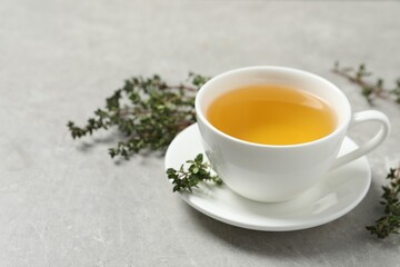 Aromatic herbal tea with thyme on light grey table. Space for text