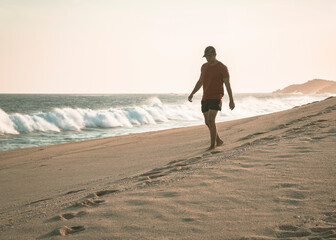 hombre caminando solo en la playa al atardecer