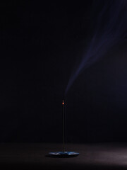 A pinch of mysticism- An incense-holding dish with a lit incense in a dark environment