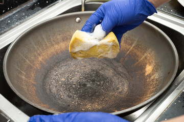 man cleaning a dirty cooking pan at horizontal composition