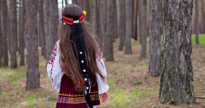 Bulgarian girl in traditional folklore costume running in forest of majestic mountain, 4k slow motion video. Bulgaria nature and people.
