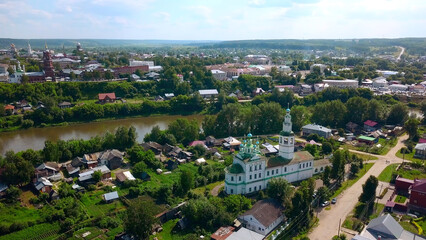 Top view of beautiful church in town by river in summer. Clip. Old colorful church in town by river on sunny day. Beautiful landscape of town with river and ancient churches in summer
