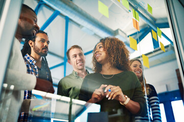 It takes people to make success a reality. Shot of colleagues having a brainstorming session with sticky notes at work.