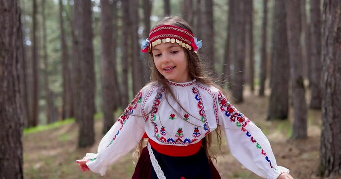 Bulgarian girl in traditional folklore costume running in forest in mountains, 4k slow motion video. Bulgaria nature and people.