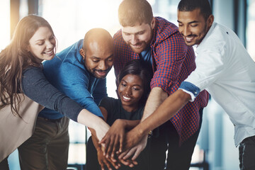 Sticking together in the name of success. Shot of a young work group joining hands in solidarity.