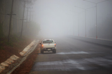 Obraz na płótnie Canvas Car driving on the asphalt road with fog in early morning