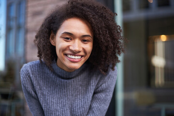Close-up beautiful African American young woman smiling a cheerful toothy smile looking at camera