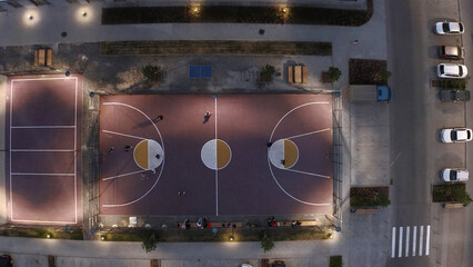 Top view of modern grounds of residential complex. Stock footage. Luxurious courtyard of modern residential complex. People play football on lighted playground in courtyard of complex