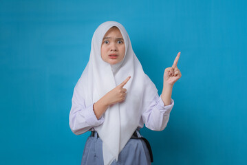 Young student woman with hijab unhappy and pointing to the side