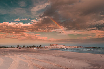 Fototapeta na wymiar Paisagem com arco íris na praia