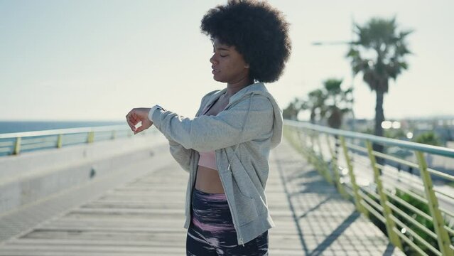 African american woman using stopwatch running at seaside