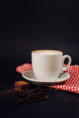 cup of coffee with milk on red blanket and black background