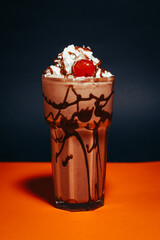 chocolate milkshake with cream and cherry on a dark background
