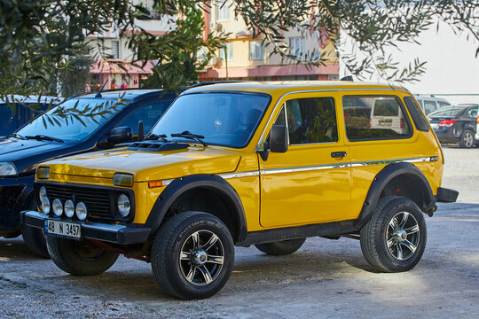 Side, Turkey - February  11, 2023:    yellow Lada Niva  is parked  on the street in city against the backdrop of a house