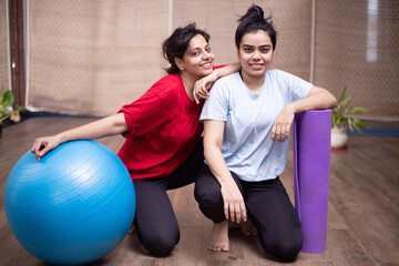 Fototapeta na wymiar Two Beautiful young happy indian woman at indoor yoga class or studio.