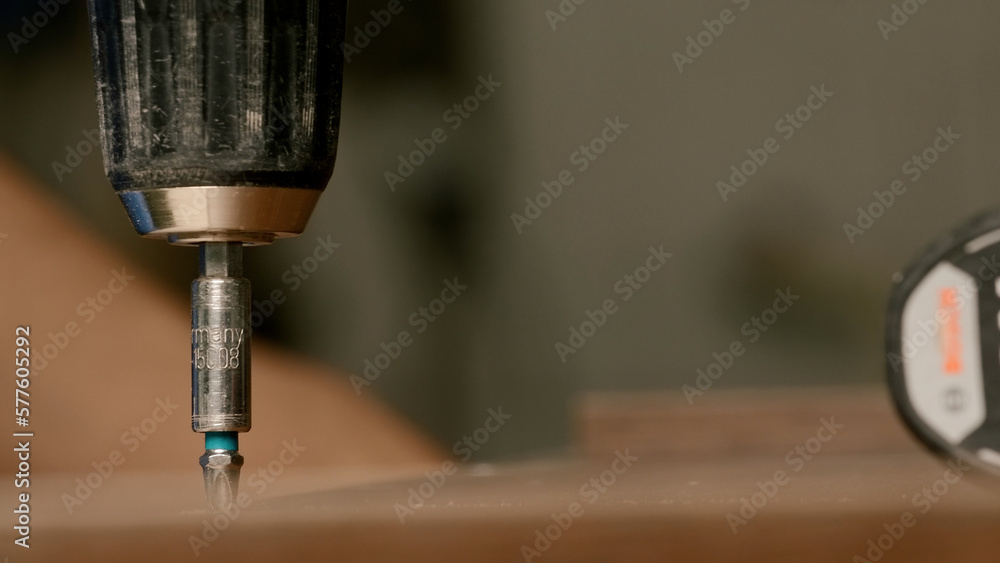 Poster close up of a man carpenter using screwdriver while working with a wooden product. creative. woodwor