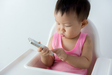 asia baby boy sitting on chair in the living room and playing with smartphone