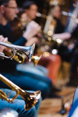 A musician playing a trumpet in a trumpet section of an orchestra during rehearsal